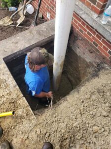 A Precision Plumbing & Drain Cleaning worker excavating around a large pipe during a job in Chesapeake, VA