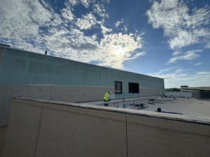 A worker performing exterior wall repair and finishing on a building for CWC Interiors in Tulsa, OK.