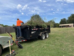 A tree service worker feeding branches into a wood chipper from a dump trailer for Liberty Tree in Fort Smith, AR.