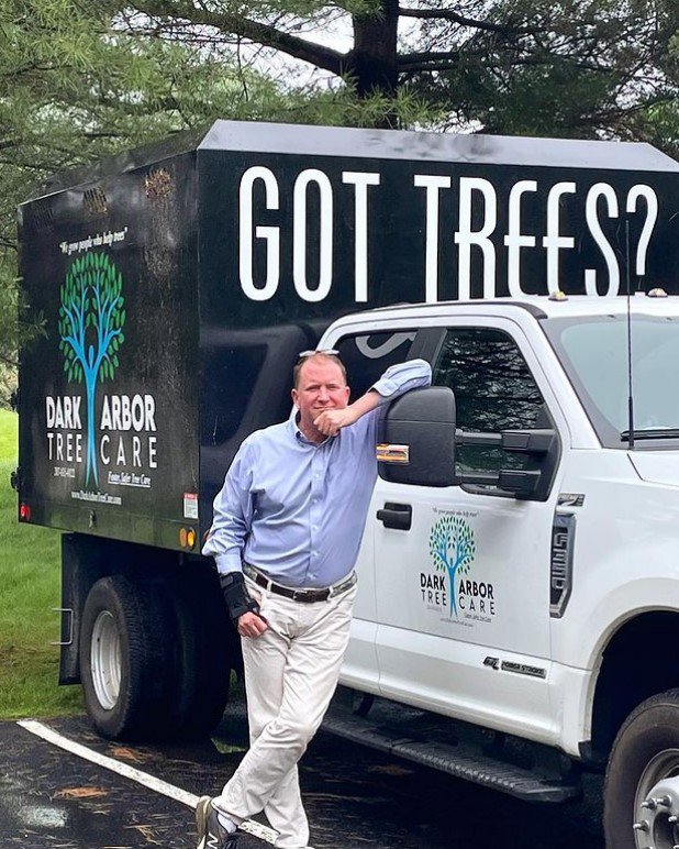 A worker feeding tree branches into a wood chipper during a tree service job by Dark Arbor Tree Care in Portland, ME.