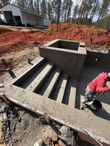 A worker finishing concrete on the steps and spa area of a pool project by Ga Impact Shotcrete in Atlanta, GA.