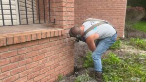 A worker from TCM Waterproofing, LLC grinding into a brick foundation as part of waterproofing preparation in Canton, OH.