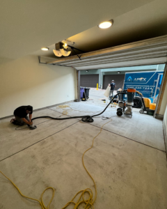 A worker grinding a concrete garage floor for preparation by Apex Custom Coatings in Middleton, WI