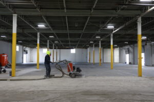 A worker grinding a concrete floor for surface preparation by Alpine Painting and Sandblasting Contractors in Paterson, NJ.