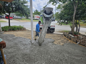 A worker guiding concrete from a mixer truck onto a reinforced area by Requena Concrete San Tex in San Antonio, TX