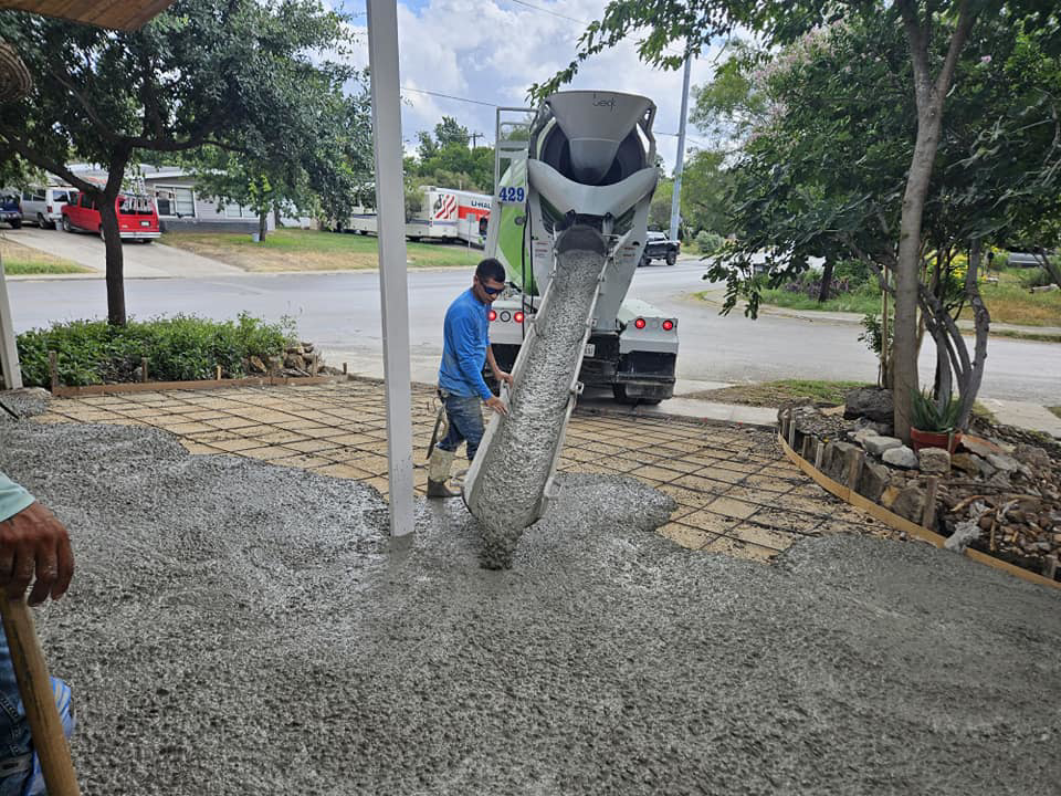A worker guiding concrete from a mixer truck onto a reinforced area by Requena Concrete San Tex in San Antonio, TX