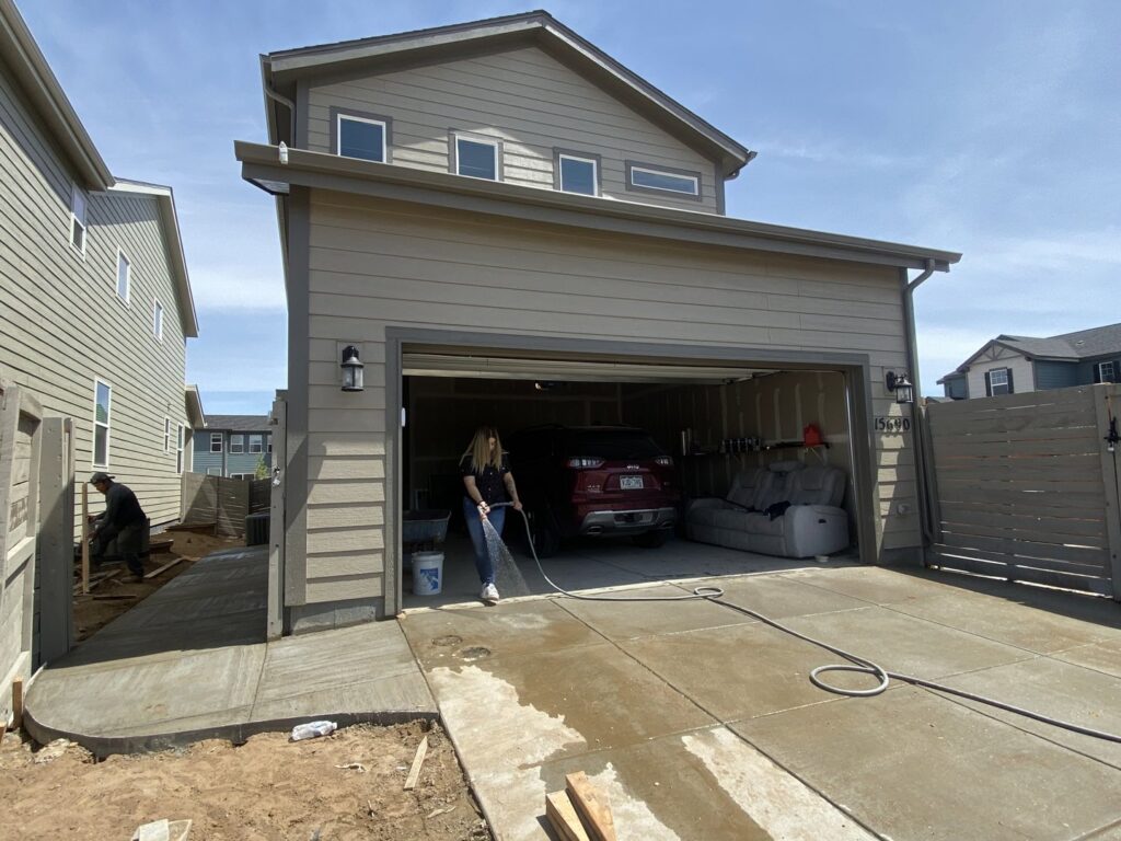 A worker hosing down a newly installed concrete path, ensuring a clean finish by Vazquez Quality Construction Inc in Aurora, CO.
