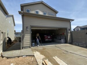 A worker hosing down a newly installed concrete path, ensuring a clean finish by Vazquez Quality Construction Inc in Aurora, CO.
