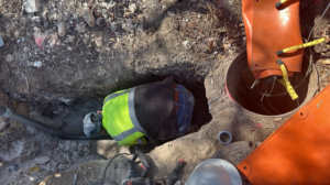 A worker in a high-visibility vest installing utilities in a trench for Stealth Civil Contracting in Austin, TX.