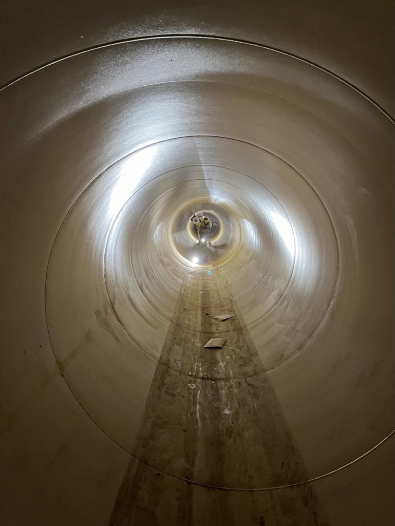 A worker performing maintenance or inspection inside a large industrial pipe for WW Enroughty & Son, Inc. in Richmond, VA.