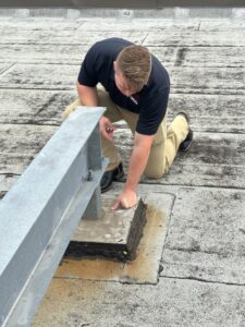 A Riker Home Services worker inspecting a commercial flat roof for damage or leaks in Plano, TX