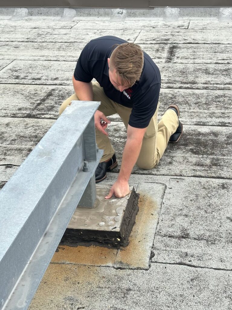 A Riker Home Services worker inspecting a commercial flat roof for damage or leaks in Plano, TX