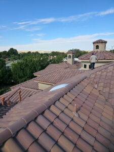 Worker inspecting a complex tiled residential roof by Campos & Son Roofing and Construction in El Paso, TX