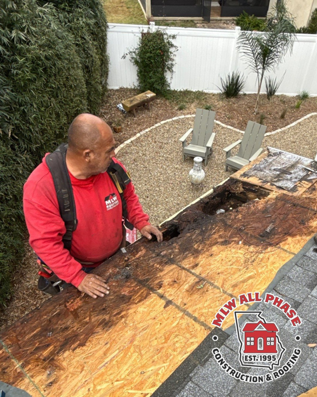 A worker from MLW All Phase Construction & Roofing inspecting a damaged roof in Athens, GA.