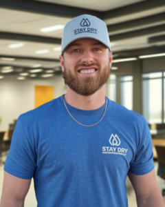 A worker inspecting a foundation wall with waterproofing membrane installed at a job site for Stay Dry Waterproofing in Marysville, OH.