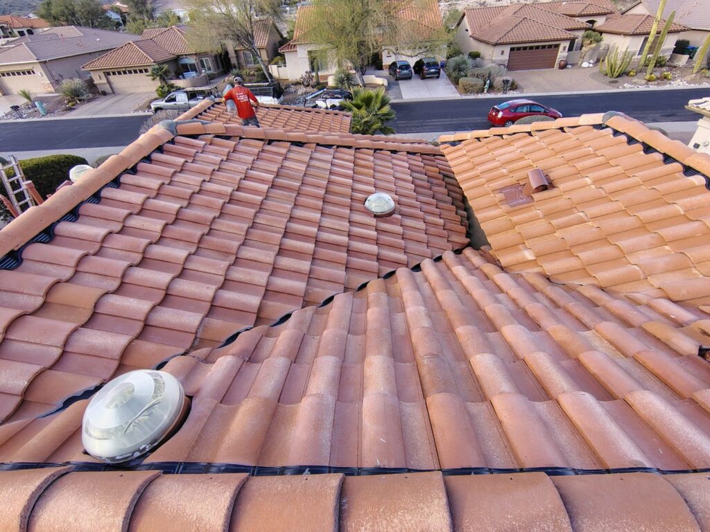 A handyman from Mayitos roofing LLC inspecting a tile roof in Tucson, AZ.