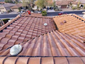 A handyman from Mayitos roofing LLC inspecting a tile roof in Tucson, AZ.