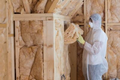 A worker in protective gear installing batt insulation for Ohio Insulation & Manufacturing Co in Dayton, OH.