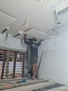 A skilled worker installing ceiling drywall and managing electrical wiring for TechPro Constructions in Houston, TX.