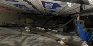 A worker installing insulation in a crawl space for Mincin Insulation Service Inc. in Pittsburgh, PA