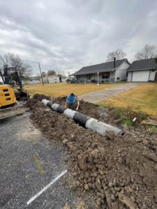 A worker installing large drainage pipes in a trench with an excavator for Rolloff Rentals / Rolloff Services in Port Angeles, WA.