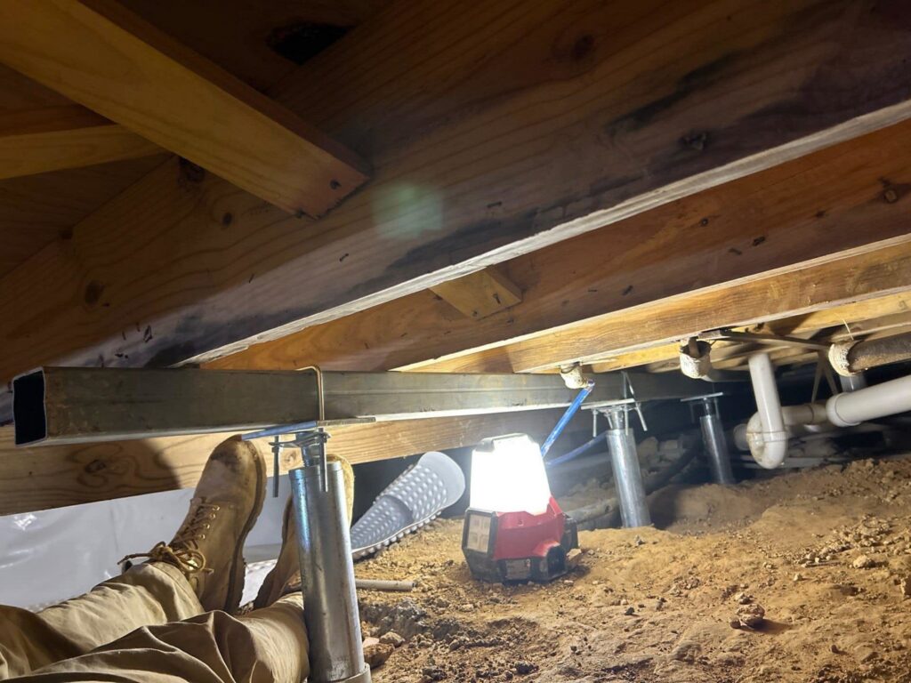 A worker installing new foundation support beams in a crawlspace for Appalachian Foundation Services in Roanoke, VA.
