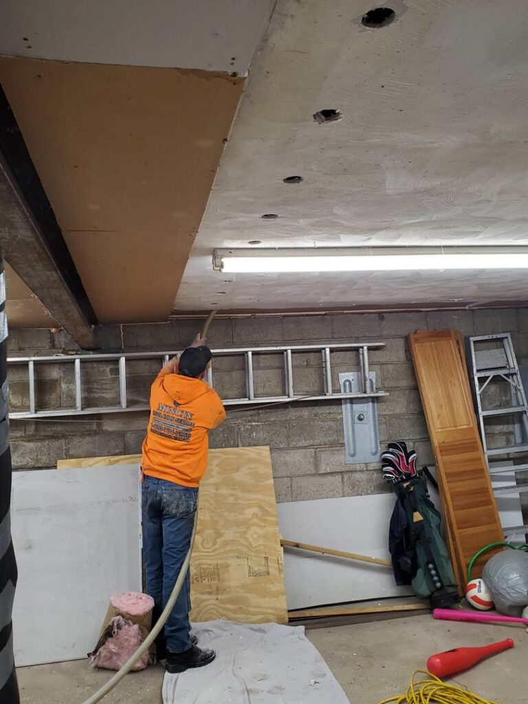 A worker installing insulation on a garage ceiling as part of a project by Mincin Insulation Service Inc. in Pittsburgh, PA.