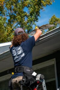 A worker installing a gutter guard on a residential gutter system by The Brothers that just do Gutters in Sioux Falls, SD.