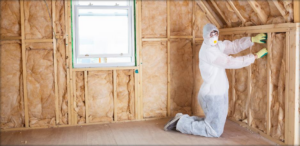 A worker in protective gear installing insulation batts for Attic Insulation of Memphis in Byhalia, MS.