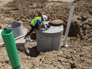A worker in a hard hat and safety vest installing a sewer pipe in a trench for Top-Notch Plumbing, Heating & Air in Greeley, CO.