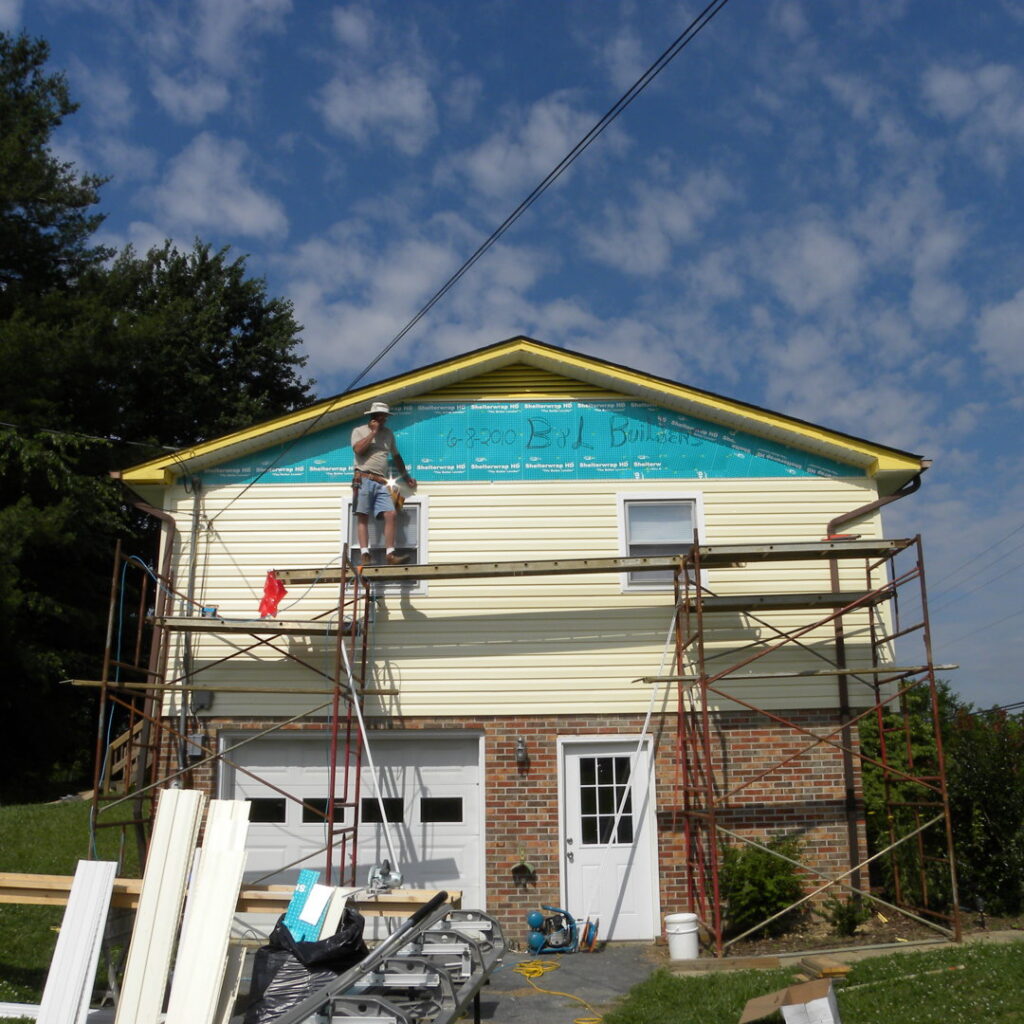 A worker on scaffolding installing siding on a house exterior by B & L Builders in Jonesborough, TN