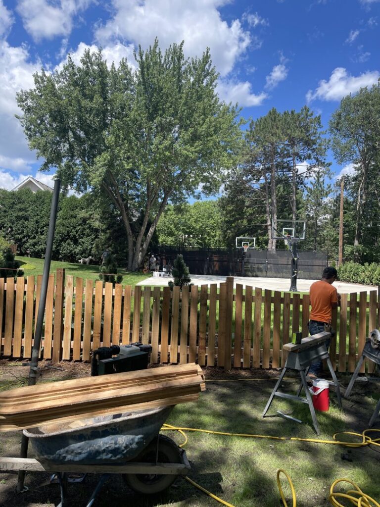 A worker installing a new wooden fence for a residential property by Security Fence & Construction Inc in Minneapolis, MN.
