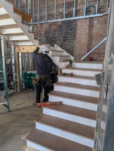 A skilled worker installing a new wooden staircase, showcasing quality craftsmanship by Infinity Building Services, Inc. in Bowie, MD.
