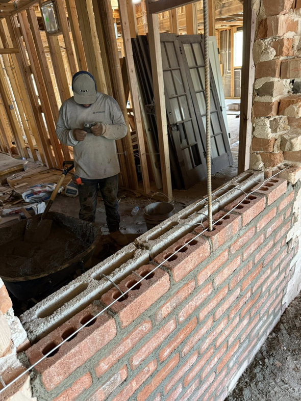 A worker laying bricks for a new wall inside a building, demonstrating masonry work by Milflores King Construction LLC in Glendale, AZ