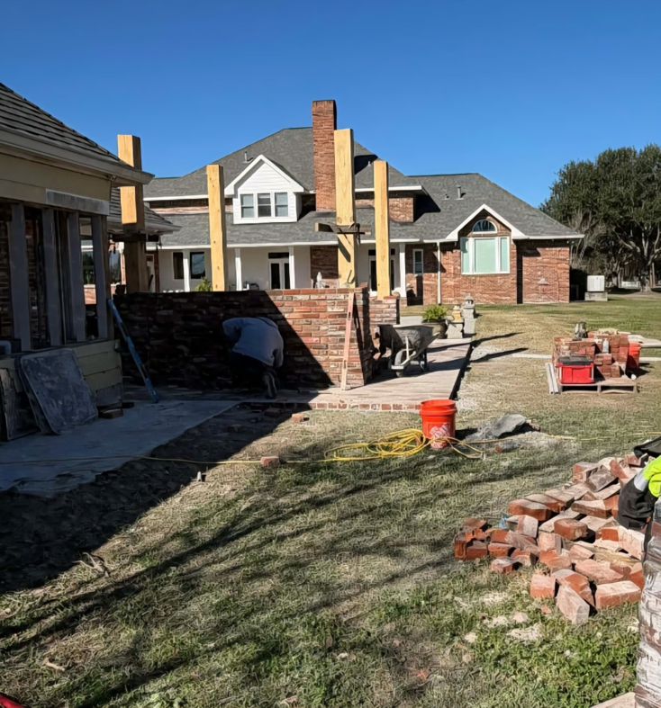 A worker laying bricks for an outdoor patio and kitchen structure by Equity Construction in Lake Worth, FL.
