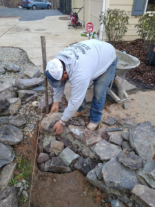 A worker carefully laying stones for a masonry project by Camacho's Construction in Durham, NC