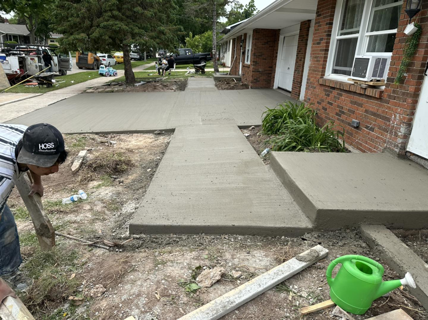 A worker leveling fresh concrete for a new sidewalk installation by R&A Concrete Home Solutions LLC in Appleton, WI.