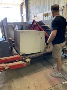 A WeHaul Hauling & Junk Removal team member loading a heavy appliance onto a trailer in Sioux Falls, SD.
