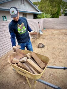 A Mora's Junk Removal & Hauling llc. worker loading bricks into a wheelbarrow for removal in Scottsdale, AZ