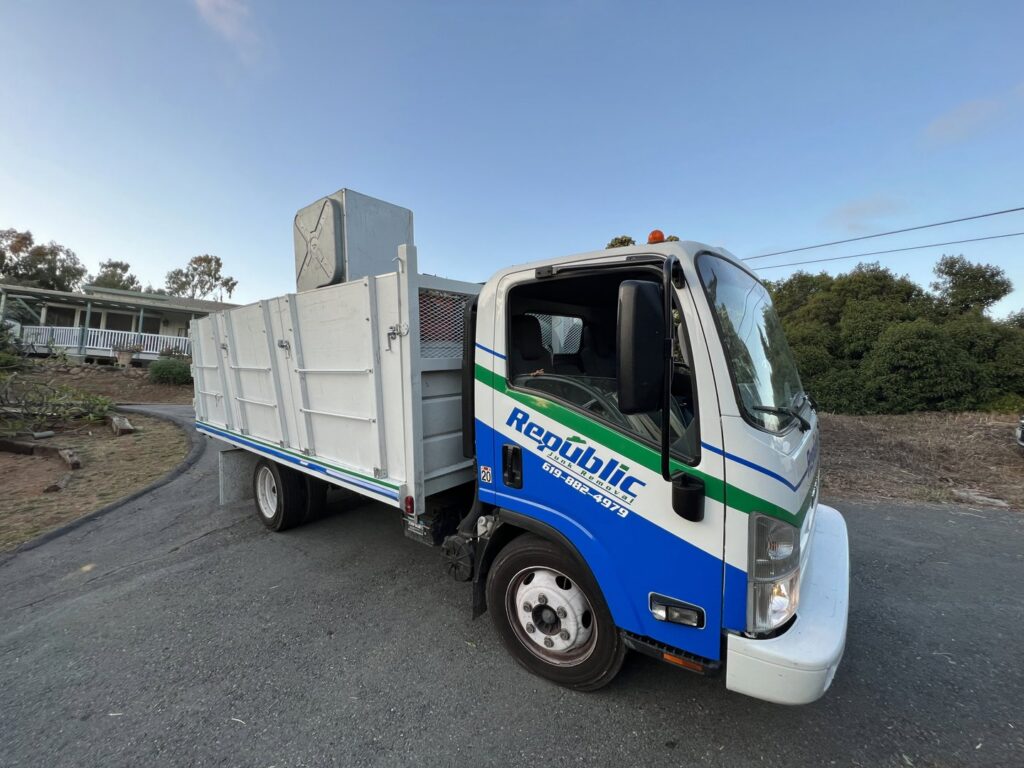 A Republic Junk Removal worker loading cardboard boxes into the back of a junk removal truck in San Diego, CA.