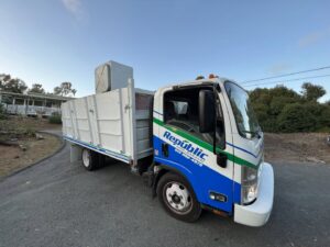 A Republic Junk Removal worker loading cardboard boxes into the back of a junk removal truck in San Diego, CA.