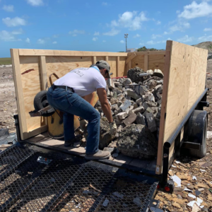 A worker loading construction debris into a trailer for Jays Haul and Junk removal service in Miami, FL.