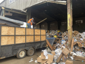 A worker from Harris Family Hauling & Snow Removal LLC loading debris into a trailer at a disposal site in Independence, MO.