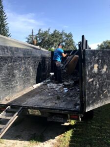 A worker loading construction or demolition debris into a junk removal trailer for Pro Dumpsters & Junk Removal in Orlando, FL.