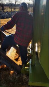 A worker from FJD Waste Disposal and Recycling LLC assisting with loading a green dumpster for junk removal in Dallas, TX.