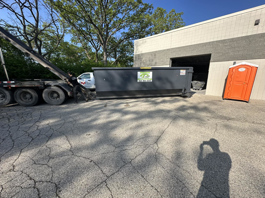A worker operating a roll-off truck to load a dumpster at a job site for Premier Recycling and Disposal in Waukesha, WI.