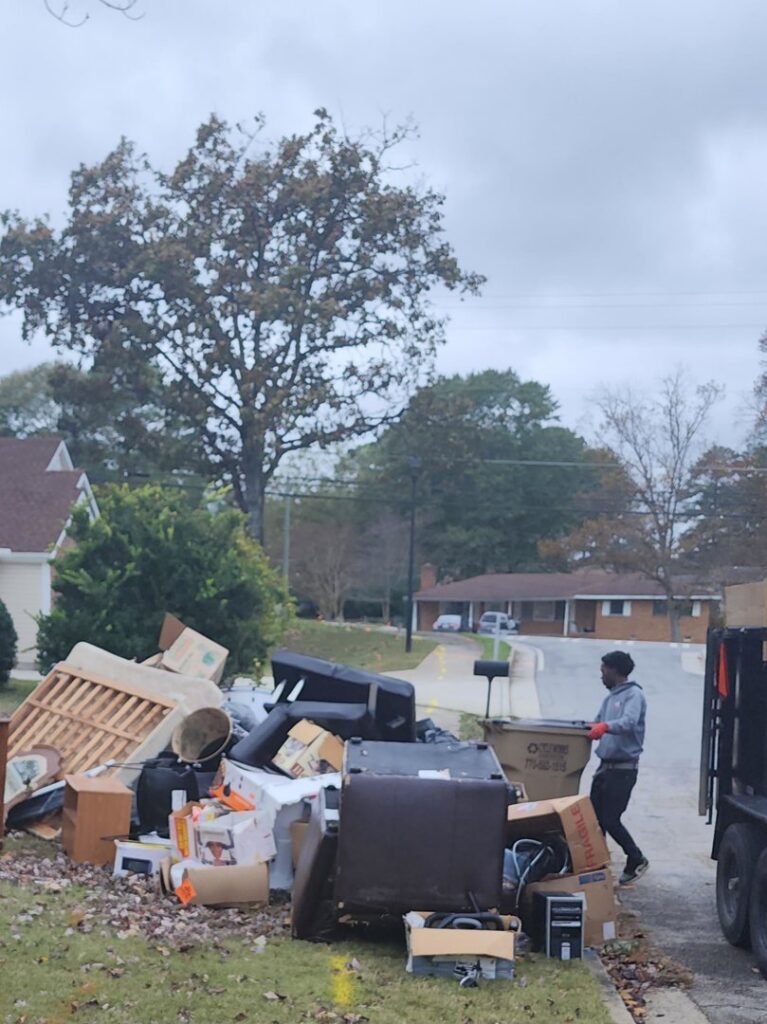 A GoGo Junk Removal worker loading a large pile of furniture and boxes into a truck in Atlanta, GA.