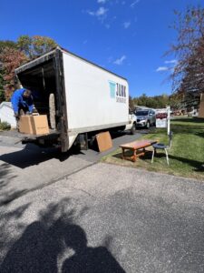A Junk Dunkers worker loading boxes and items into a removal truck in Wrentham, MA