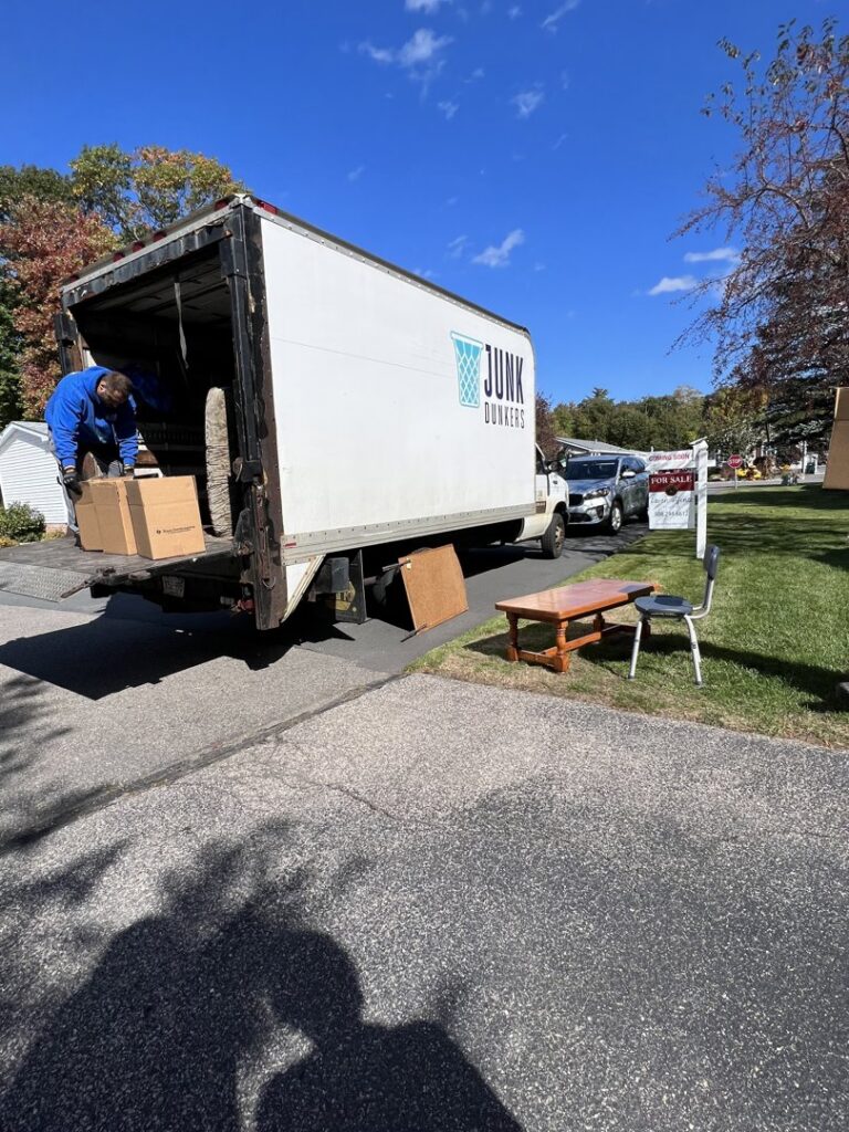 A Junk Dunkers worker loading boxes and items into a removal truck in Wrentham, MA