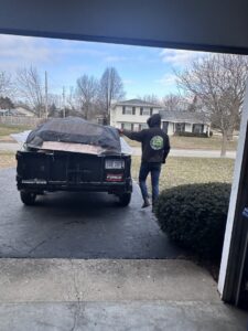 A 614junkremoval team member standing next to a trailer loaded with junk covered by a tarp in Columbus, OH.